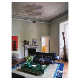 Interior shot of a living room featuring a dark leather sofa, a glass coffee table, and classical architectural moldings.