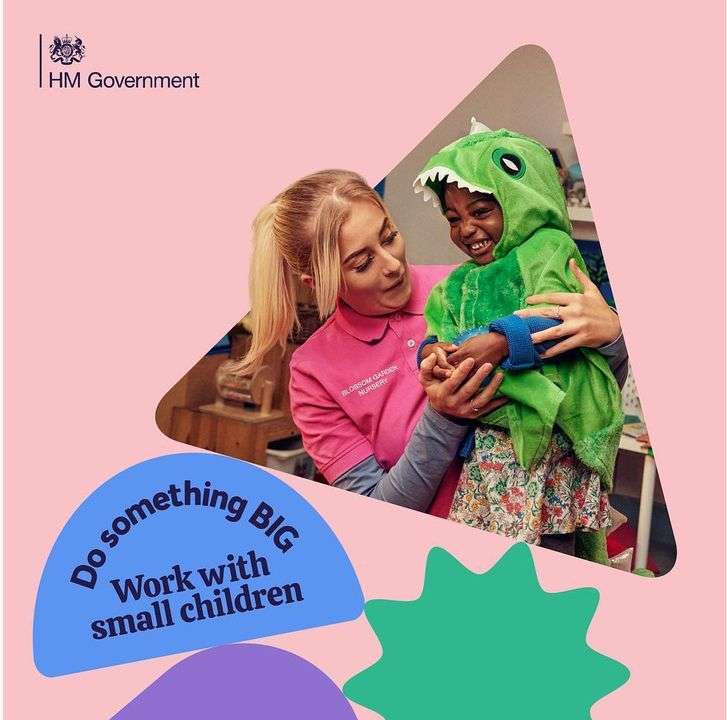 Teacher and young child dressed in a green dinosaur costume hug indoors, promoting work in childcare with the HM Government logo visible.