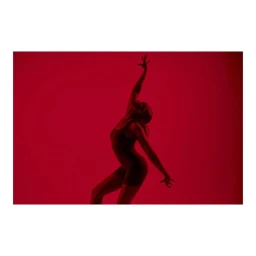 Dancer in a dark leotard posing dramatically against a solid red studio background in London by Simon Winnall