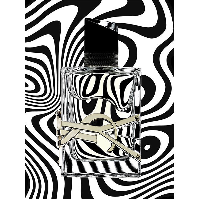 Studio shot of a glass fragrance bottle with a black cap and gold accents, set against a graphic black and white patterned backdrop.