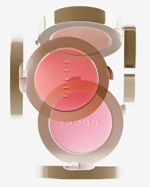 Three Gucci blush compacts stacked, featuring pink and coral shades, displayed on a white background in a product shot.
