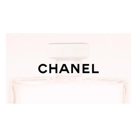 Close-up of a Chanel perfume bottle, showcasing its clear glass, white cap, and the iconic black brand name against a soft white background.