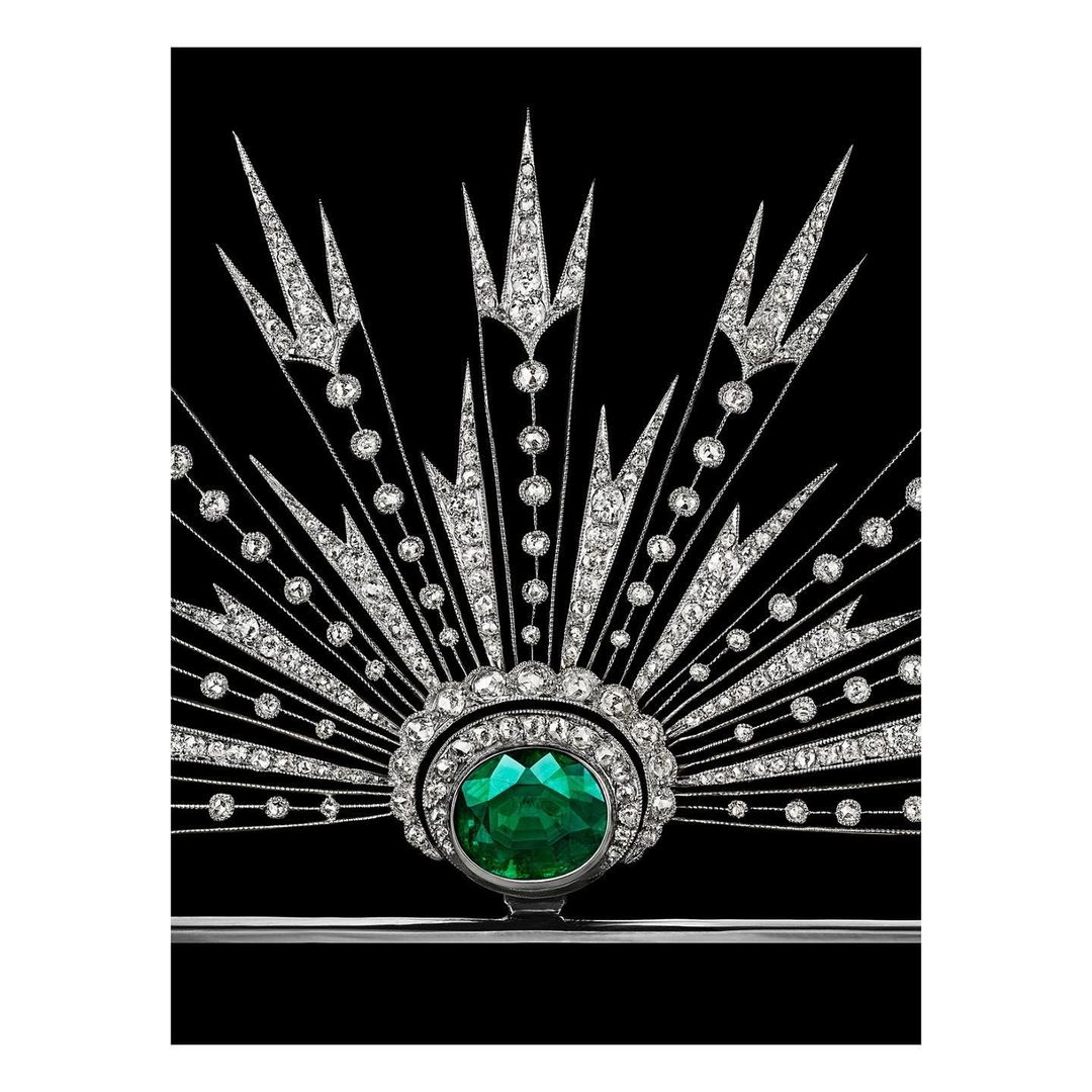Emerald and diamond jewelry brooch featuring art deco design and a silver setting against a solid black background.