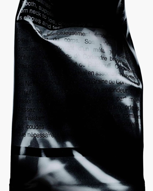 Close-up of a black product packaging with text in French and English, detailing product benefits for skin cleansing and body care.