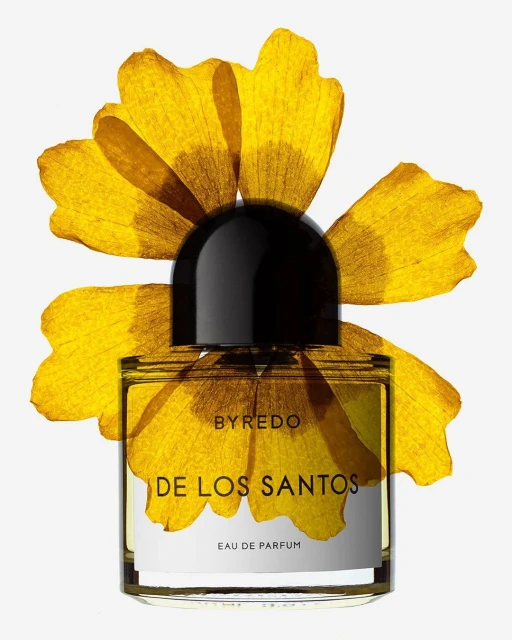 Byredo perfume bottle, DE LOS SANTOS, on white backdrop with dried yellow flower petals framing it, product shot, still life.