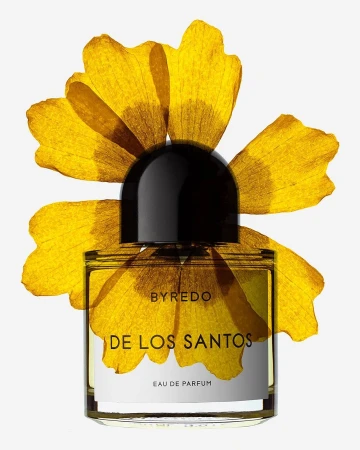 Byredo perfume bottle, DE LOS SANTOS, on white backdrop with dried yellow flower petals framing it, product shot, still life.