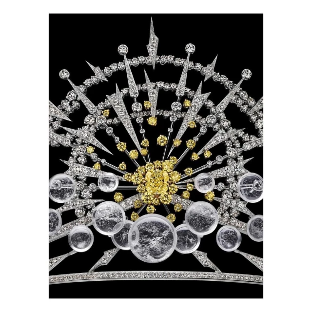 Elaborate diamond tiara featuring white and yellow diamonds in a radial starburst design, set against a stark black background.