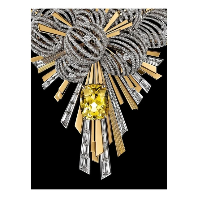 Close-up of an intricate jewelry piece featuring a large yellow gemstone surrounded by diamonds and gold, set against a black backdrop.