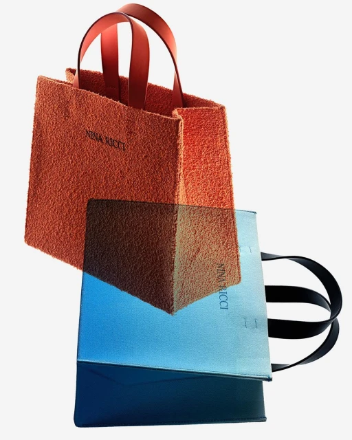 Two Nina Ricci tote bags, one textured orange with red handles, the other blue with black handles, on a clean white background.