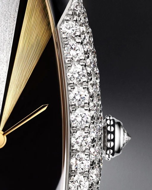 Close-up of a luxury timepiece featuring a black dial, radiant gold accents, and a diamond-encrusted silver crown, highlighting opulent design.