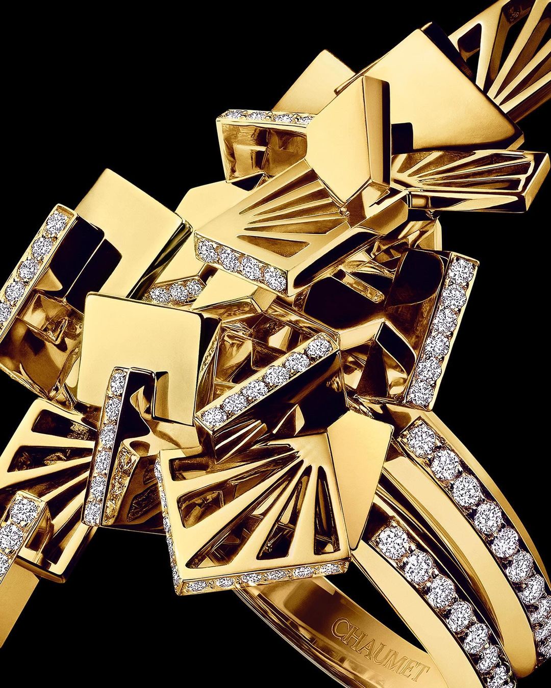 Close-up studio shot of a gold and diamond Chaumet bracelet. The jewelry features geometric shapes and luxurious materials against a black backdrop.