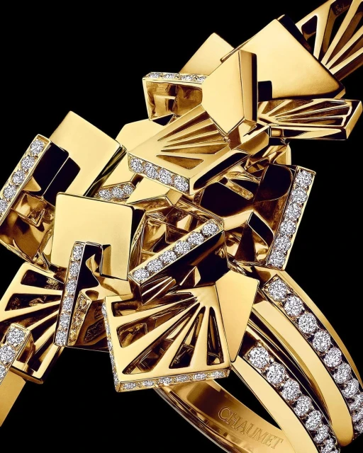 Close-up studio shot of a gold and diamond Chaumet bracelet. The jewelry features geometric shapes and luxurious materials against a black backdrop.