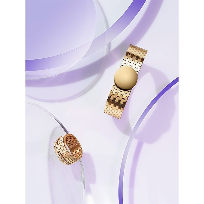 Elevated view of a gold bracelet and ring, featuring geometric designs, set against a light purple and white background with graphic elements.