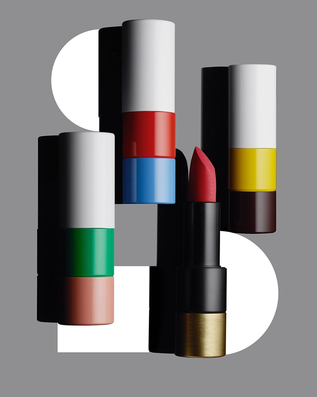 Arrangement of colourful stacked lipstick tubes with one open red lipstick by Simone Cavadini in Paris