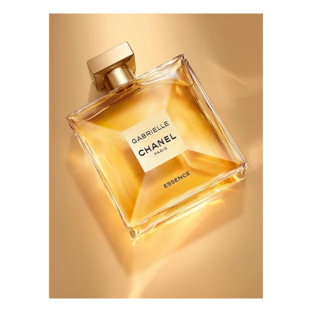 Square glass Chanel perfume bottle filled with gold liquid on a gold background, studio product shot for the beauty and fashion industries.