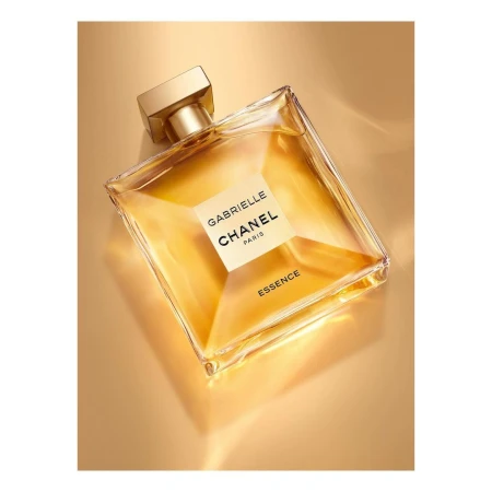 Square glass Chanel perfume bottle filled with gold liquid on a gold background, studio product shot for the beauty and fashion industries.