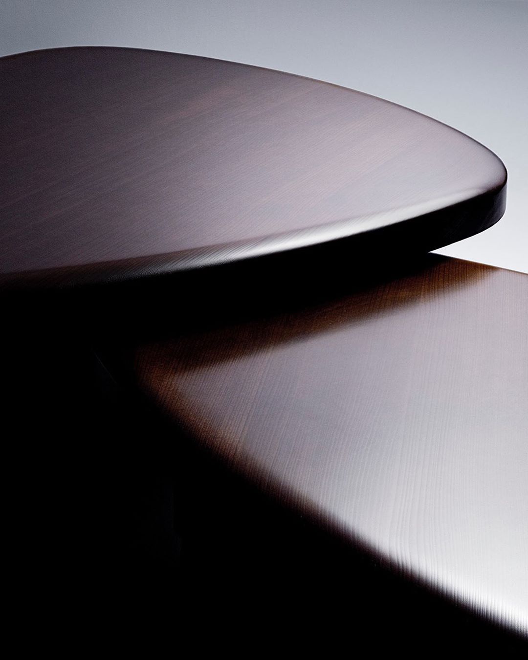 Close-up of two stacked, rounded-edge dark brown surfaces with a smooth, polished texture, creating a minimalist, abstract composition.