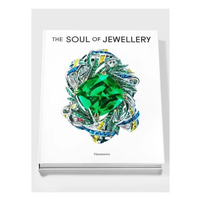 Book cover with a large green gemstone surrounded by an intricate setting of silver, gold, and colorful gemstones.