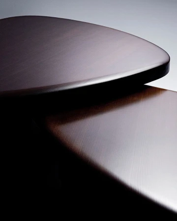 Close-up of polished dark wood surfaces with organic curved shapes photographed by Simone Cavadini in Paris.