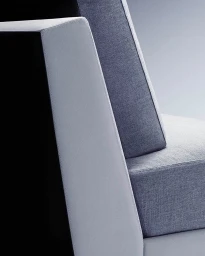 Close-up architectural view of modern upholstered chair with textured grey fabric and clean structural lines against a gradient background.