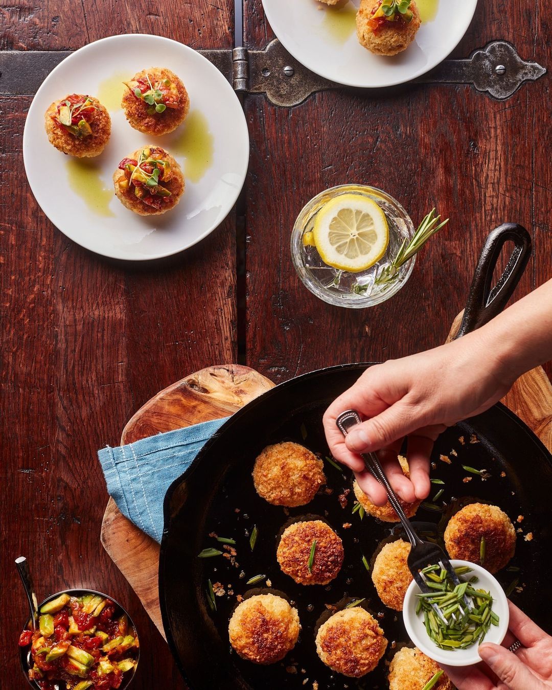 Overhead shot features food being prepared in a pan and served on plates, creating an inviting culinary scene on a rustic wooden table.