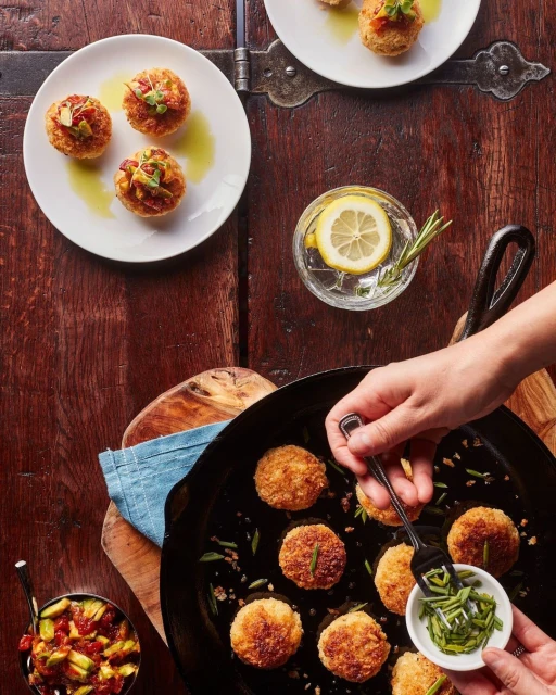 Overhead shot features food being prepared in a pan and served on plates, creating an inviting culinary scene on a rustic wooden table.