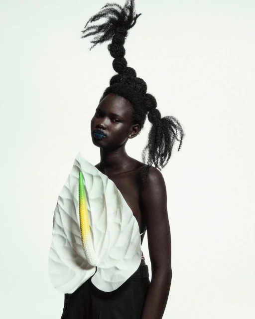 Woman with artistic black updo and floral garment against white backdrop in beauty style portrait for creative editorial fashion.
