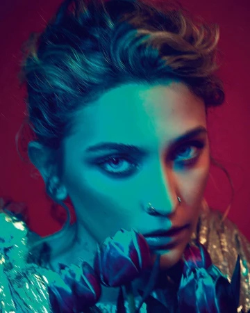Close-up portrait of a woman with light skin, wearing a glittery top, holding tulips against a red background with teal and red lighting.