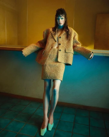 Model in textured tweed skirt suit leaning against a blue counter in Paris by Sofia Sanchez and Mauro Mongiello.