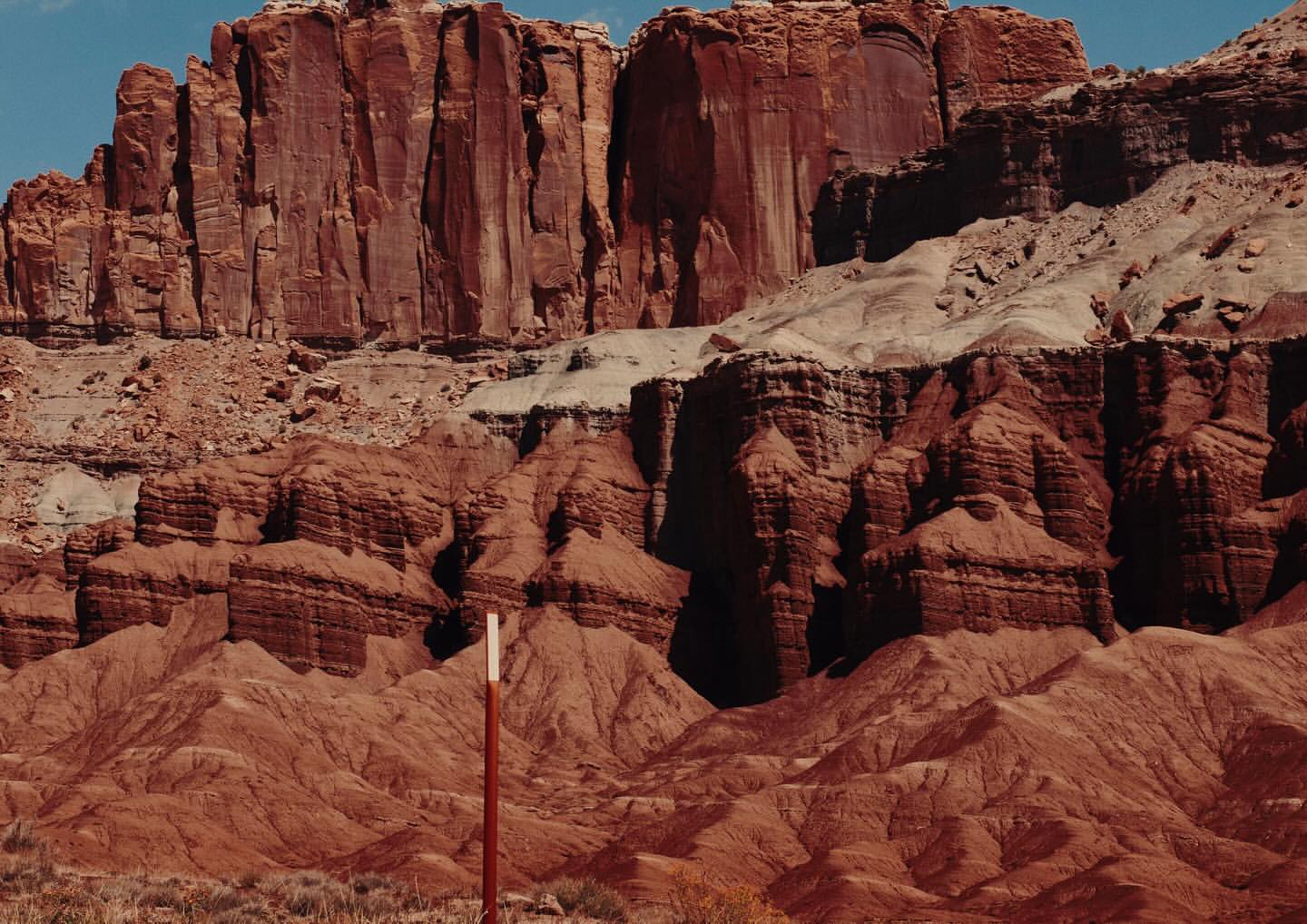 Capitol Reef National Park landscape featuring red rock formations under a clear blue sky, showcasing the rugged beauty of Utah's desert.