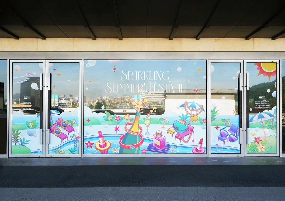 Retail storefront window display featuring a 'Sparkling Summer Festival' theme with illustrations of summer-themed beauty products and accessories.