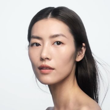 Close up portrait of an East Asian woman with dark hair against a seamless white background