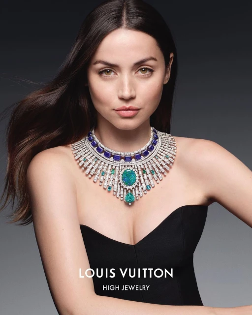 Portrait of a brunette woman wearing a black dress and an elaborate, multi-colored gemstone statement necklace for Louis Vuitton High Jewelry.