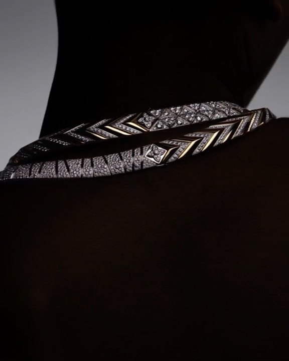 Close-up portrait of a diamond necklace worn around a person's neck against a dark background, photographed by Solve Sundsbo.