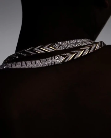 Close-up portrait of a diamond necklace worn around a person's neck against a dark background, photographed by Solve Sundsbo.