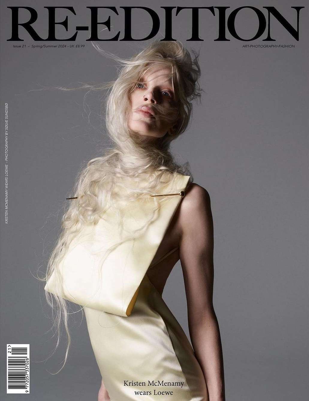 Re-Edition magazine cover featuring Kristen McMenamy in Loewe, styled in a unique dress and flowing blonde hair against a grey backdrop.