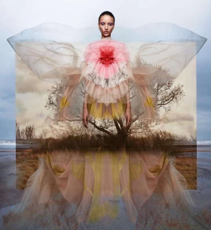 Elegant woman in a flowing pink and yellow gown, standing against a beach landscape, creating a surreal fashion portrait with soft lighting.