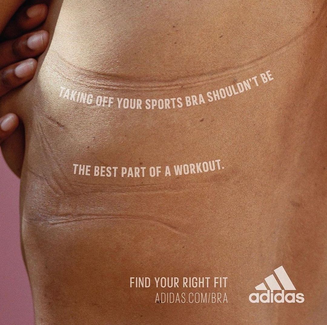 Close-up shot of a woman's torso with skin indentations from a bra, accompanied by Adidas text ad for a sports bra.