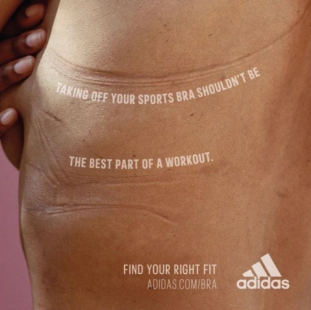 Close-up shot of a woman's torso with skin indentations from a bra, accompanied by Adidas text ad for a sports bra.