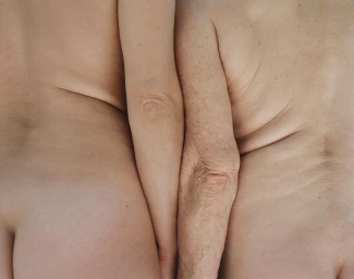 Close-up of the backs and arms of two individuals of different ages pressed together side by side