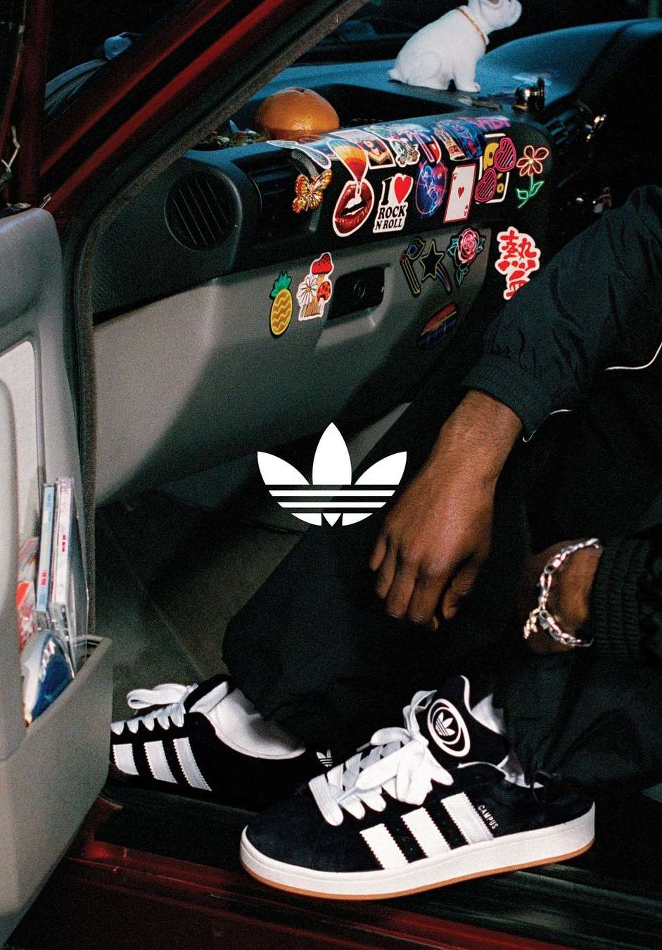 Adidas sneakers product shot inside of a car with multiple stickers. Dominant colors are black and white. The overall tone is youthful.
