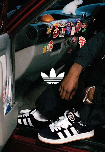 Adidas sneakers product shot inside of a car with multiple stickers. Dominant colors are black and white. The overall tone is youthful.