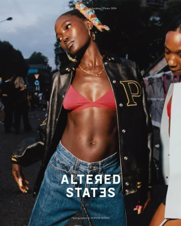 Two women model in a fashion editorial. One woman in a red bra top, jeans, and jacket is in focus in an urban outdoor setting.