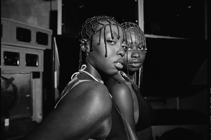 Black and white studio portrait of two women with beaded headwear, looking directly at the camera with neutral expressions.