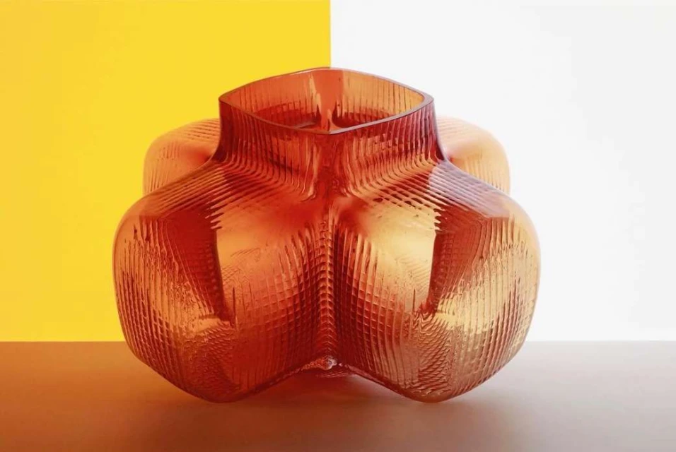 Textured amber-toned glass vase sits on a neutral surface against a split background of yellow and white, showcasing modern design.