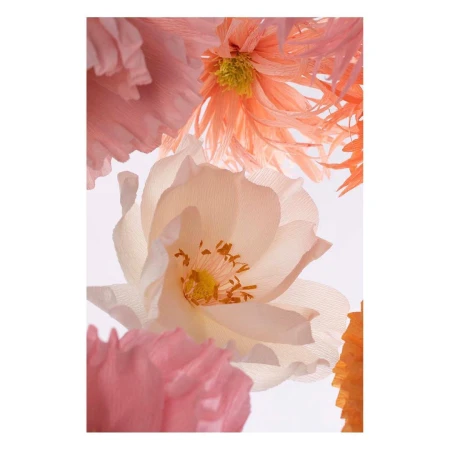 Artistic close-up of handmade paper flowers in pastel colors, including pink, peach, and white, against a bright, soft white backdrop.