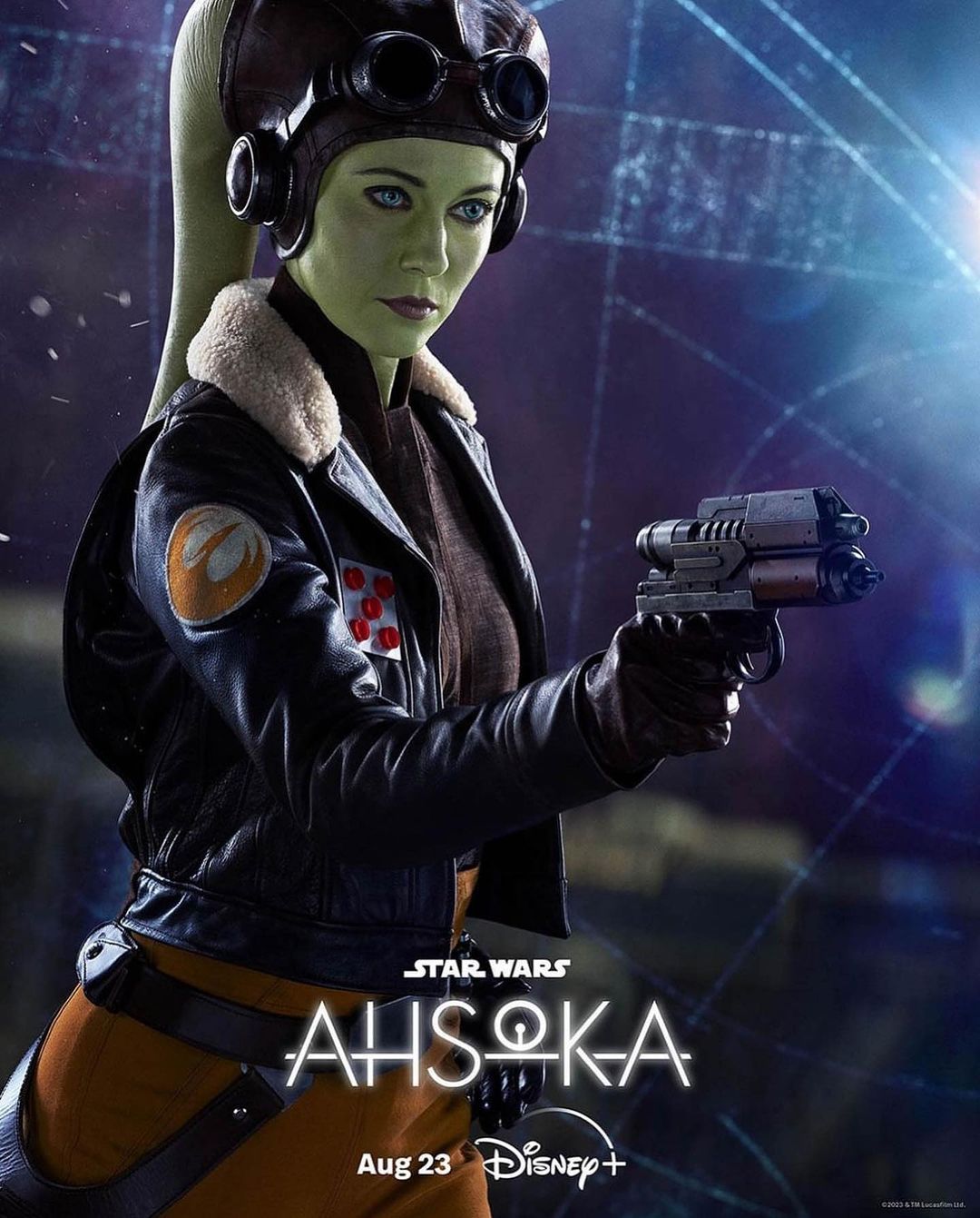 Live-action poster of Ahsoka Tano, Star Wars character, in pilot gear with blaster, against a geometric dark blue background for the series Ahsoka.