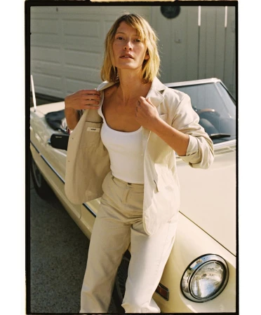Woman in neutral suit leaning against vintage convertible car shot by Spencer Wells