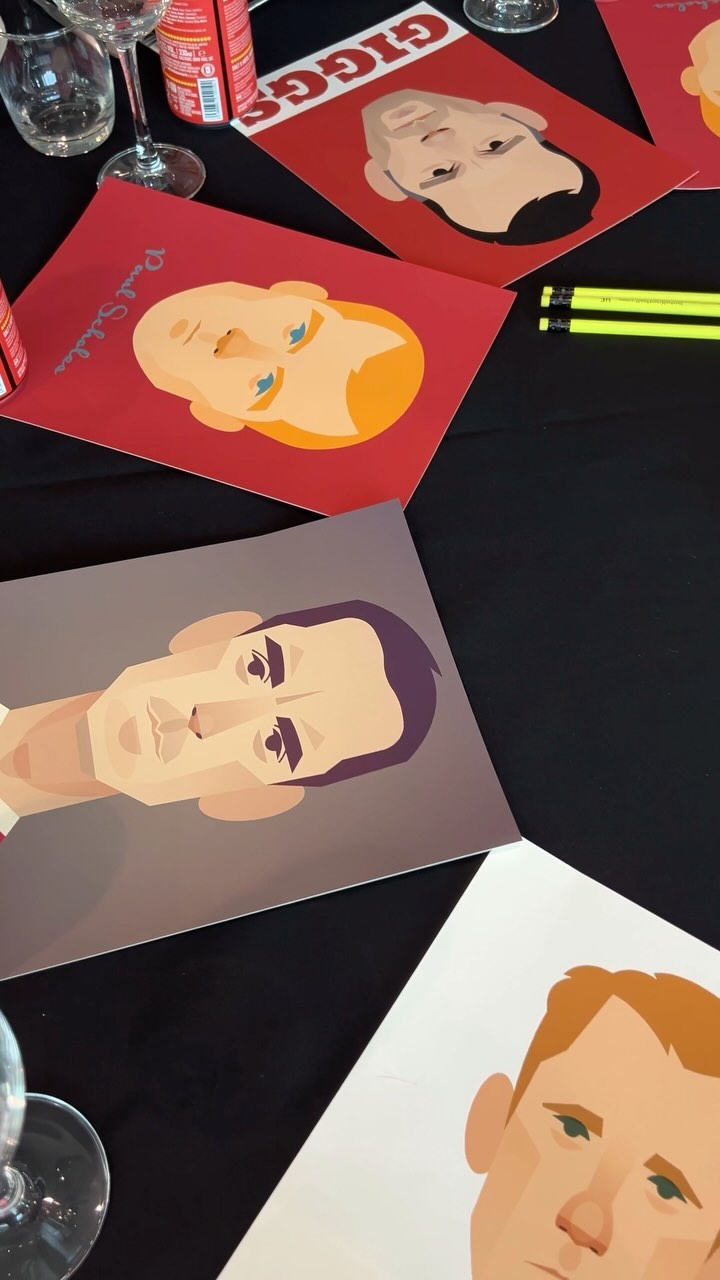 Close-up view of illustrated posters featuring stylized portraits on a black surface with wine glasses and pencils, creating a colorful, artistic scene.