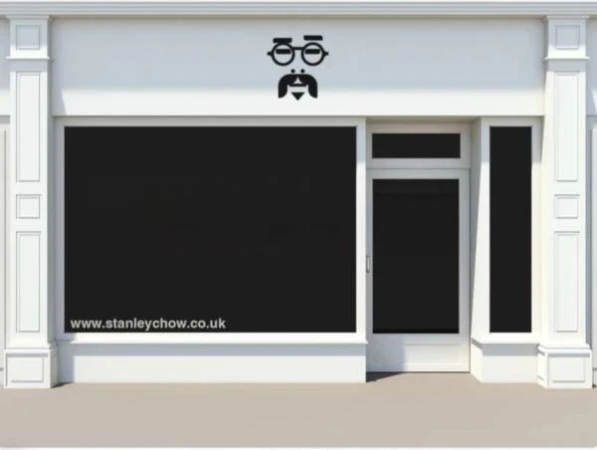 Exterior of a building with a blacked-out storefront and a logo of a face above the storefront window, along with a website address below.